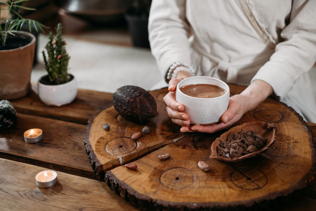 Person giving ceremonial cacao in cup. chocolate drink top view